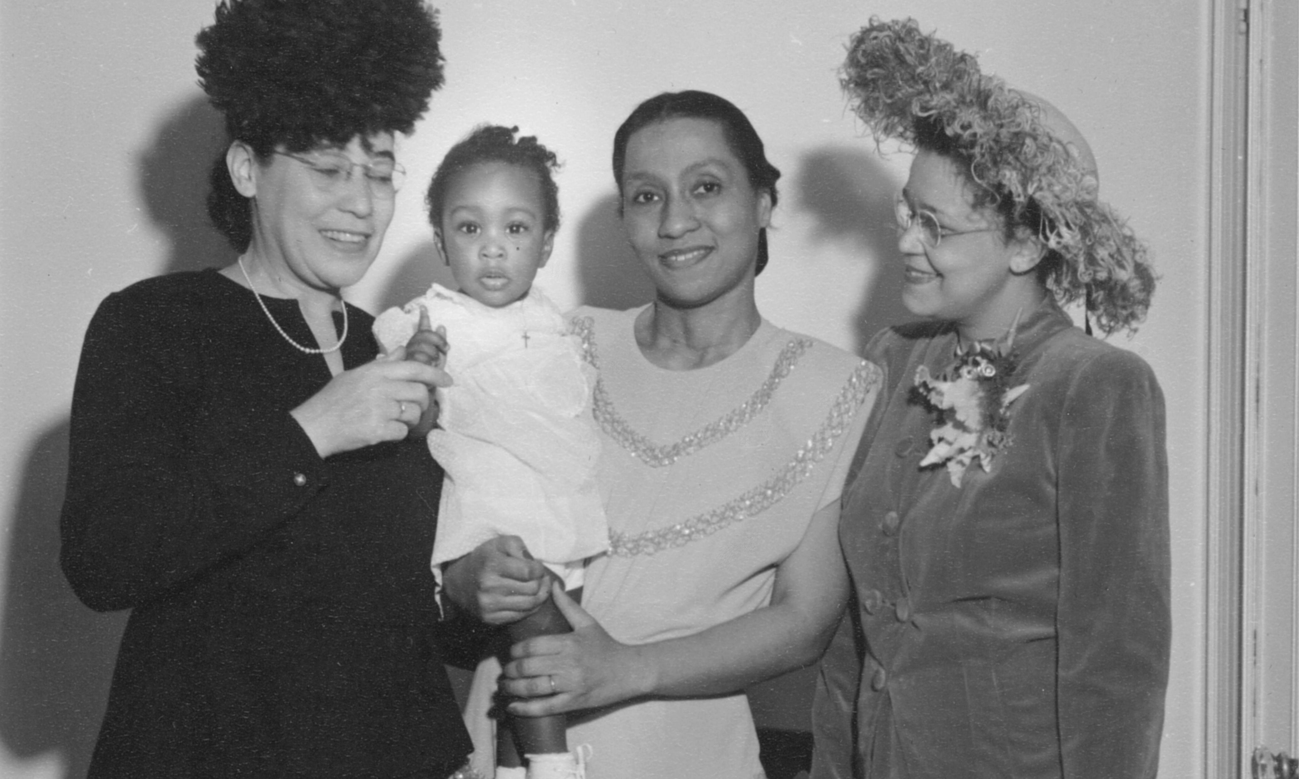 Dickens, a young woman wearing a sparkly dress, holds her young daughter Jayne, surrounded by Virginia Alexander, MD, and Sadie Tanner Mossell Alexander
