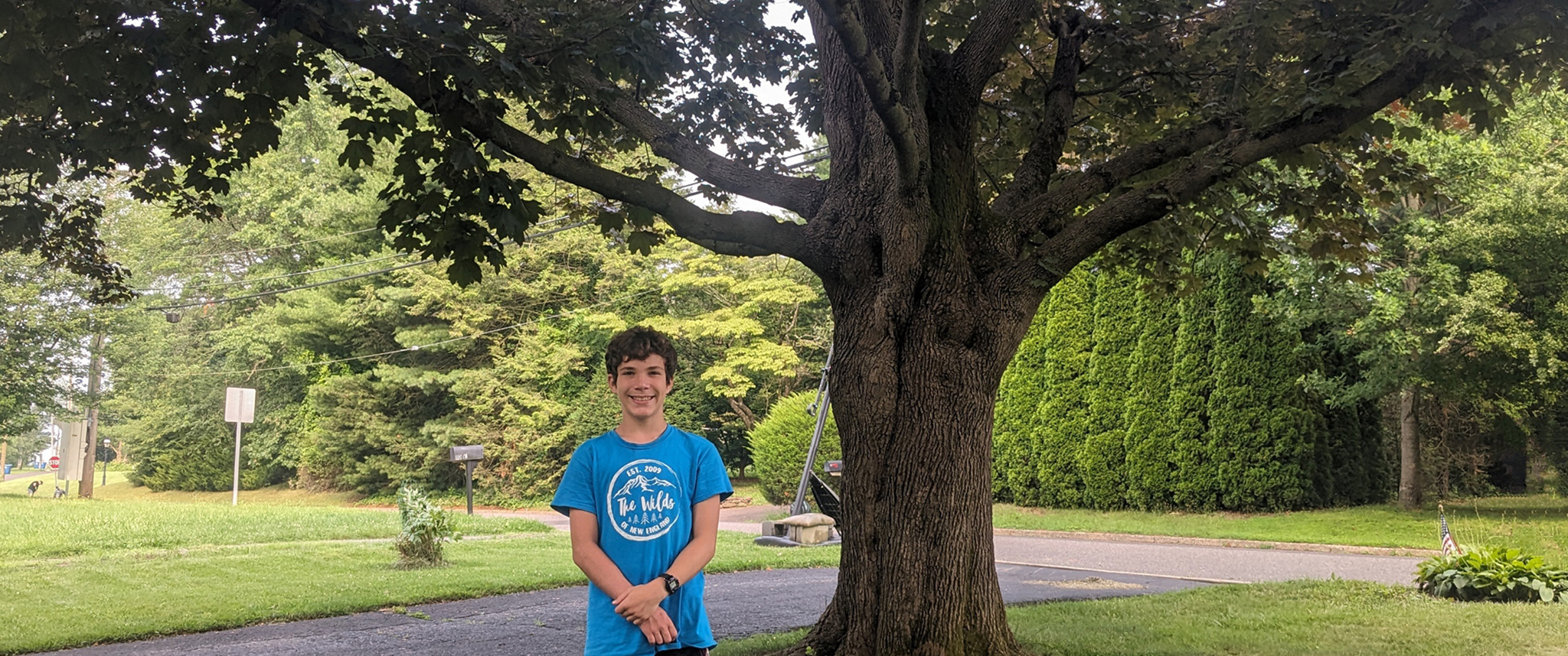 KC Myers, a teenage boy, stands in front of a large tree