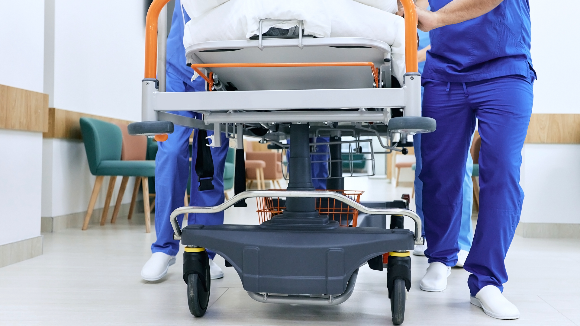 A closeup shot of the legs of medical personnel pushing a gurney down a hospital hallway.