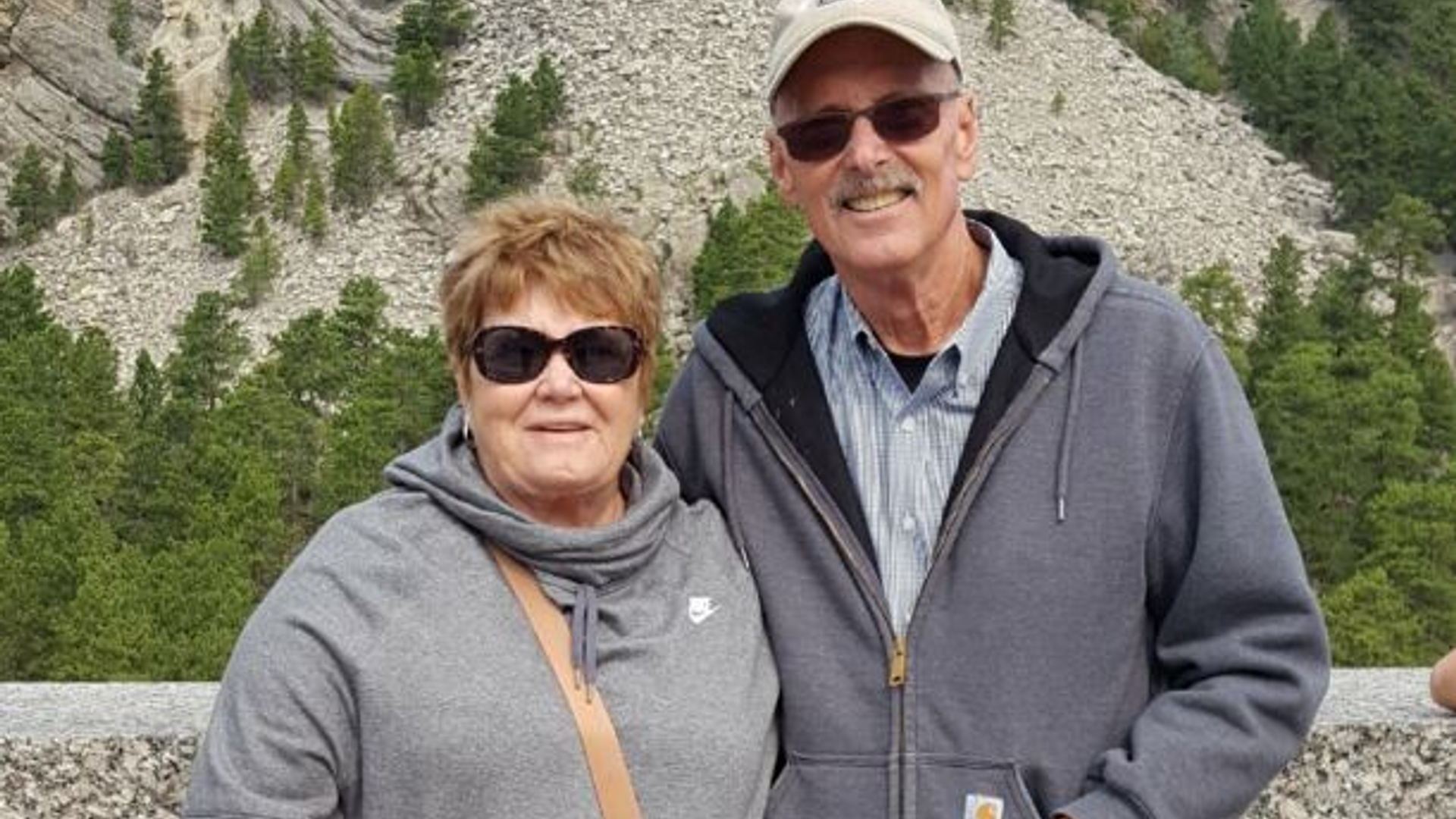 Bill and Darla Ludwig stand at a vista with Mount Rushmore in the background