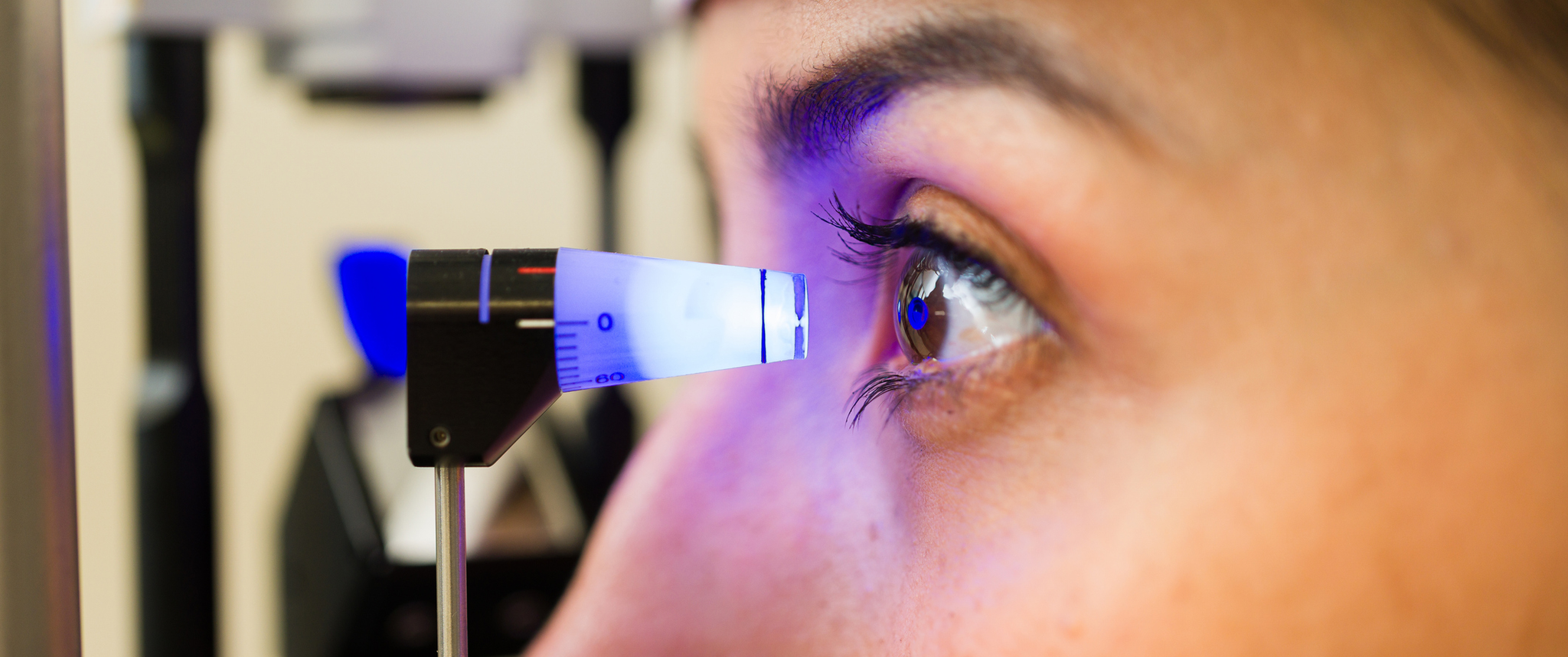 Patient receiving a diagnostic eye exam, checking intraocular pressure with a tonometer to screen for glaucoma