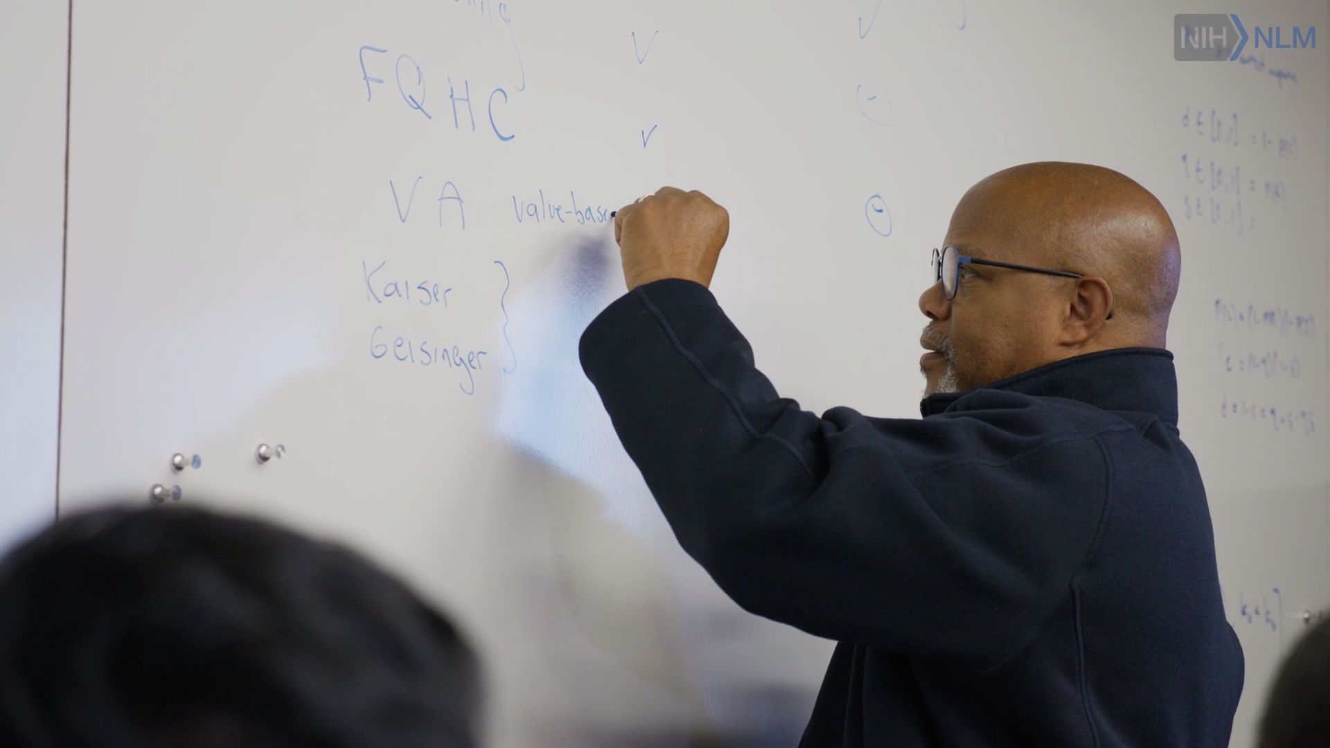 Video still of Kevin B. Johnson, MD writing on whiteboard