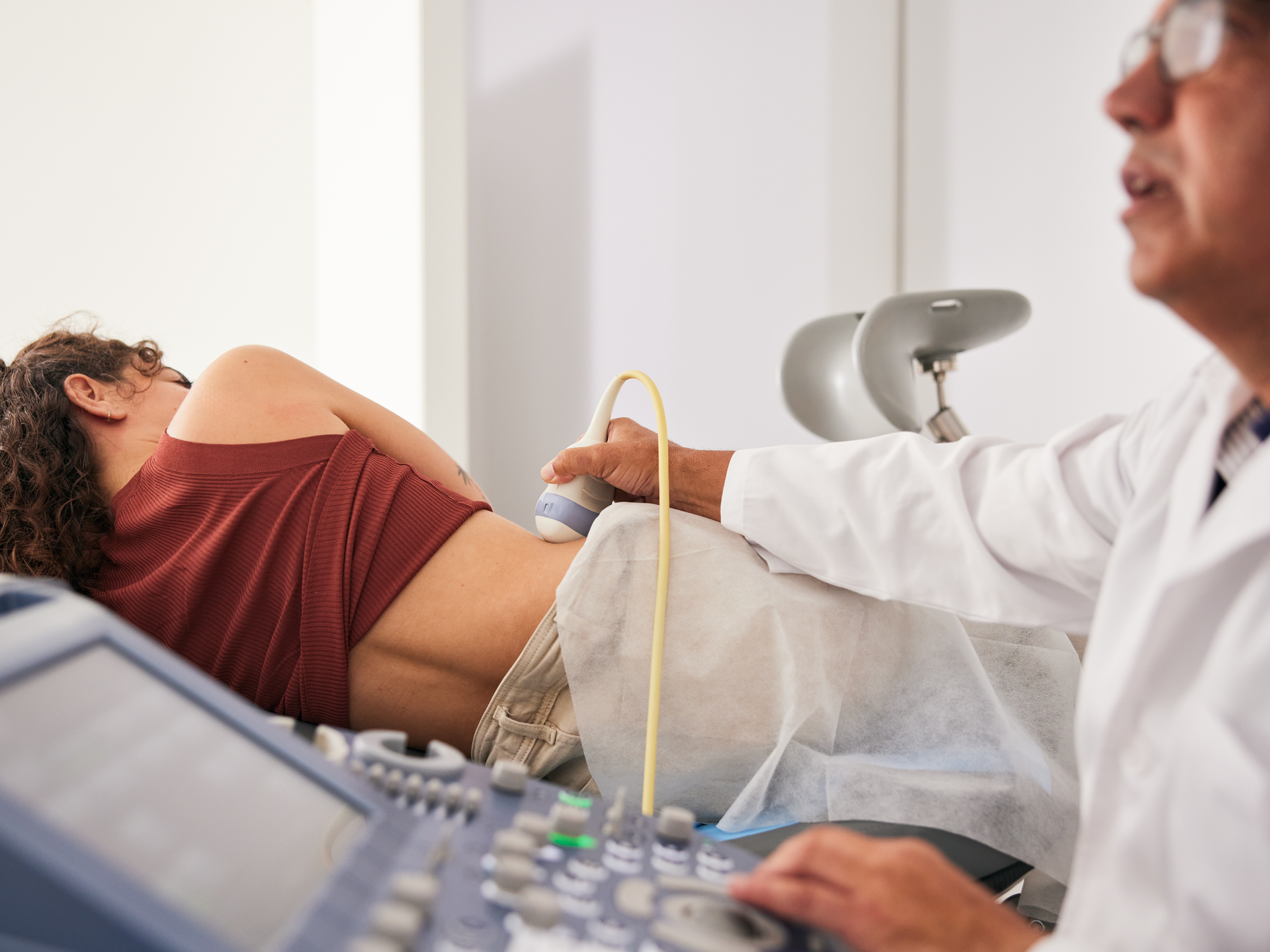 Doctor examining the woman's right kidney using an ultrasound scanner