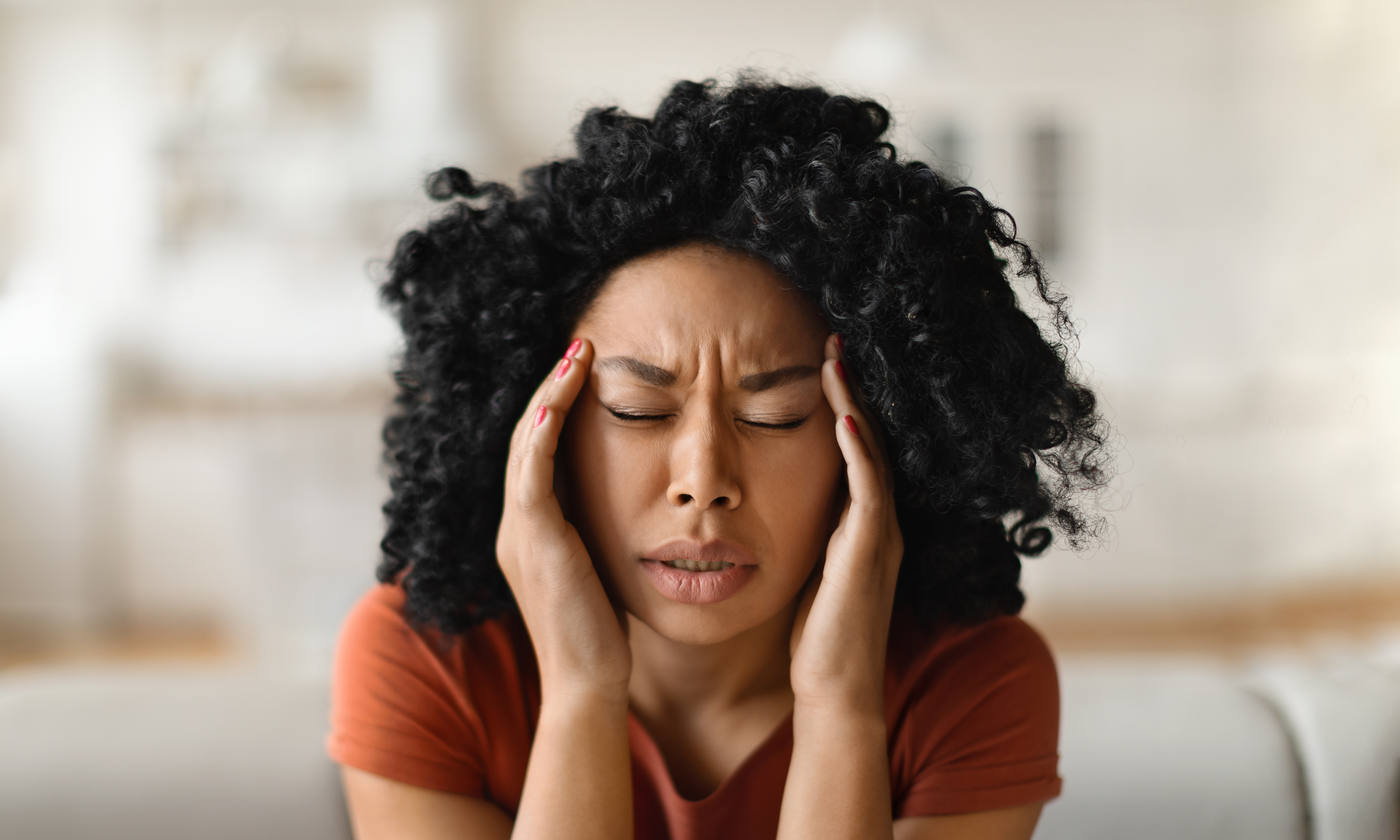 Young African American woman massaging temples, suffering acute headache while at home