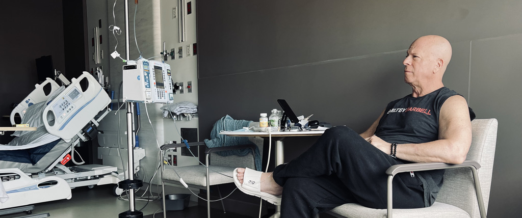 Cancer patient, Howard Aaron, sitting in patient room receiving IV therapy