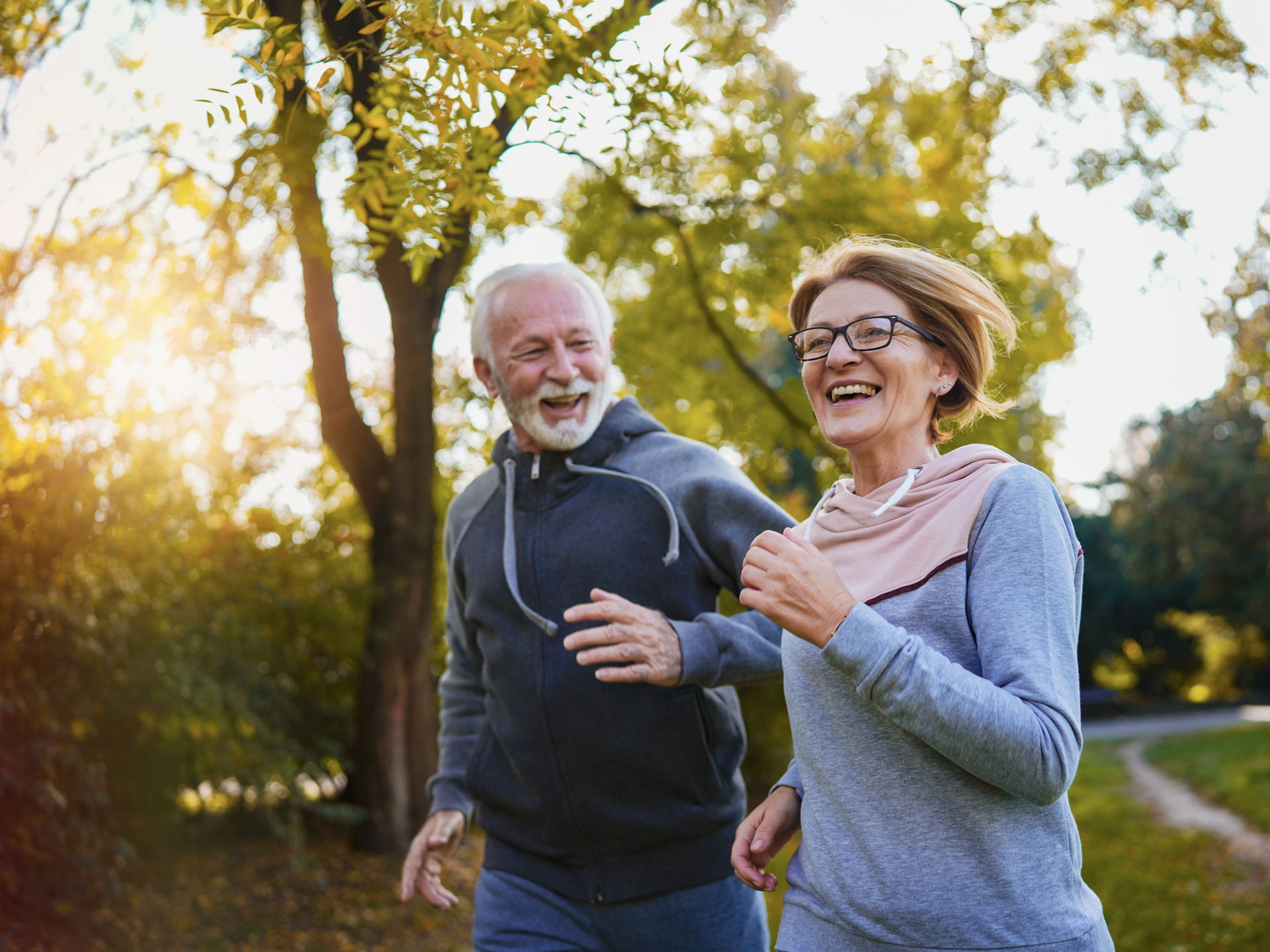 Aging couple running in a park settings.