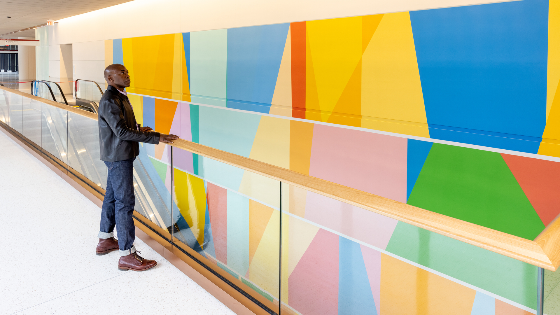 Odili Donald Odita leans on a railing looking at his colorful mural in the Pavilion