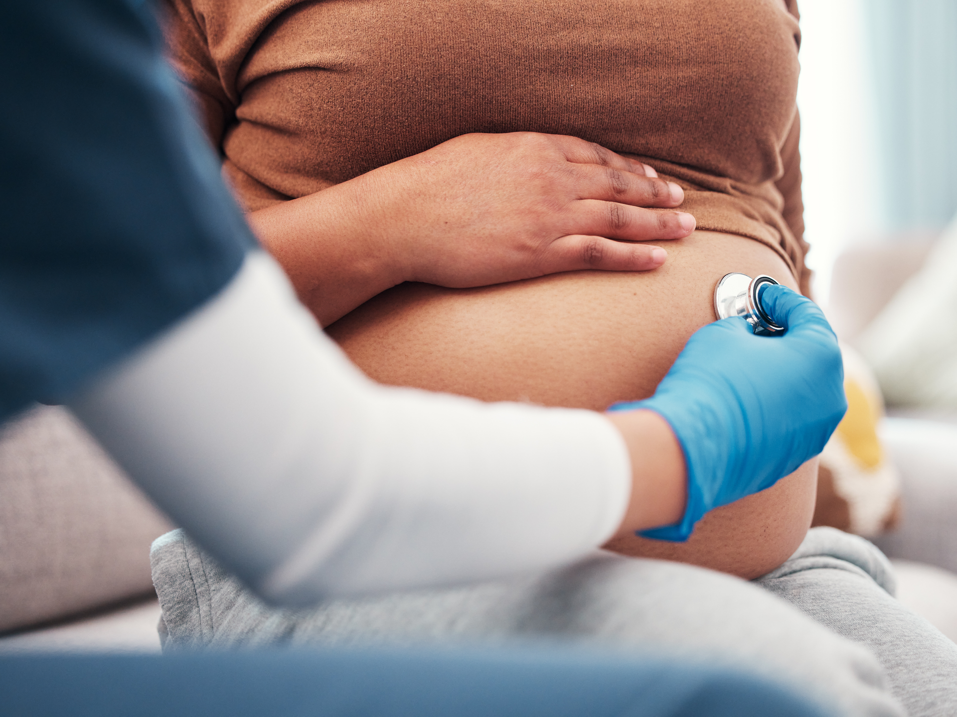 Closeup of pregnant woman's belly with nurse holding stethoscope