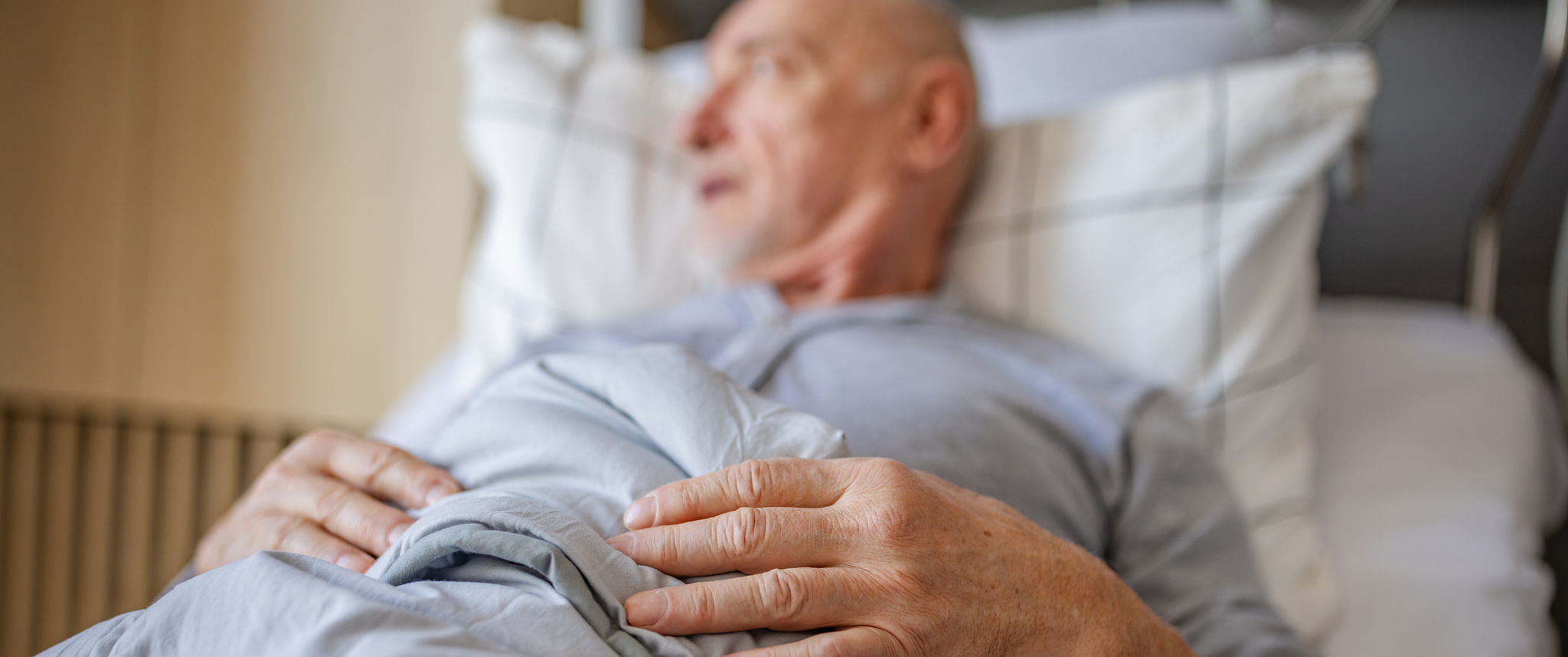 A senior man receives medical care in a hospital bed