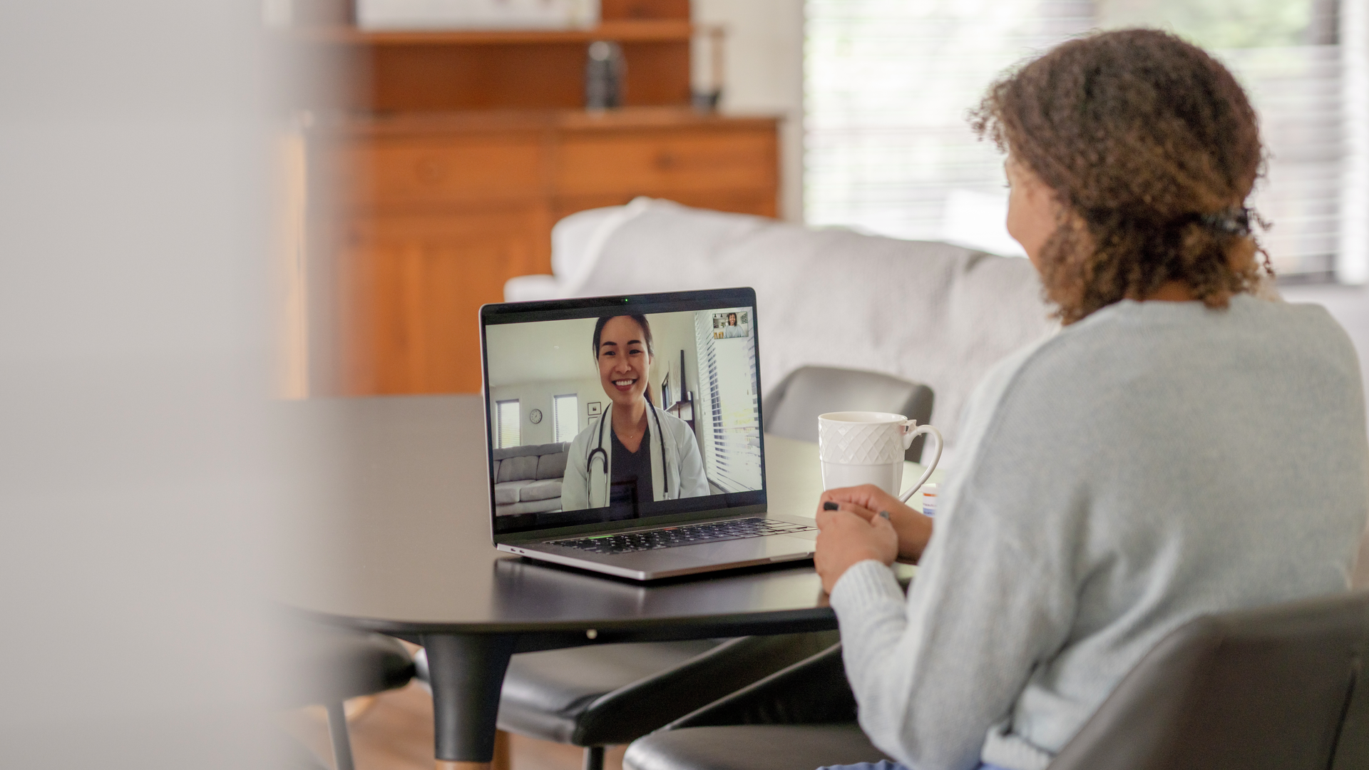 A female patent of African decent meets with her doctor remotely via a video call. 