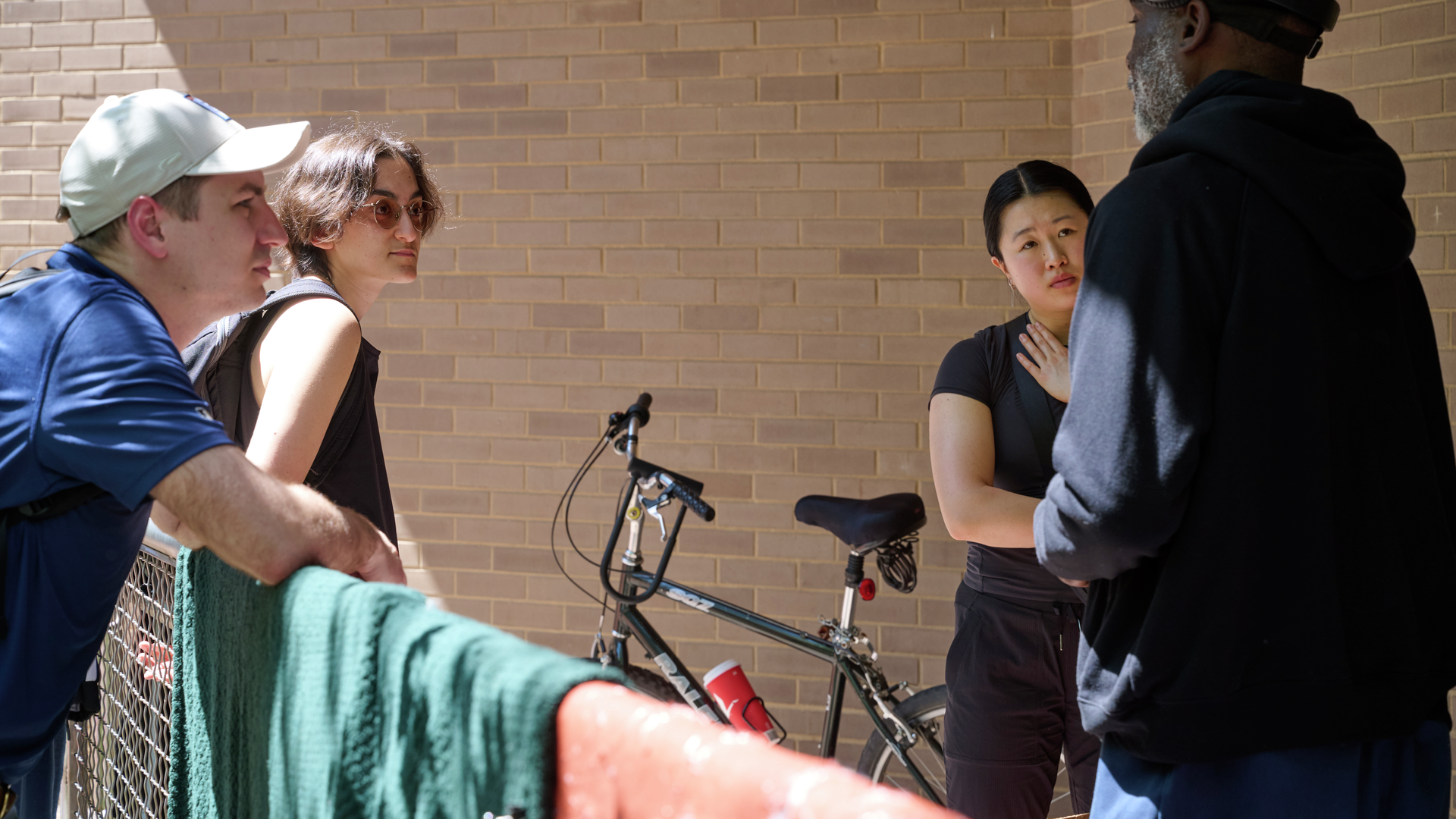 In a courtyard, two Penn medical students and family physician Zachary Kosek, MD, visit with a man wearing a black hooded sweatshirt