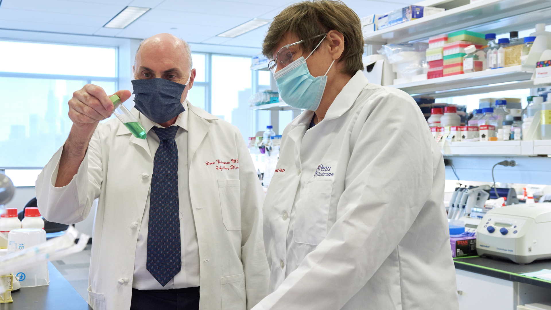 mRNA Pioneers, Drew Weissman and Katalin Kariko, look at test tube in their research lab