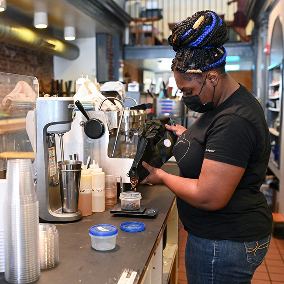 A barista pours coffee into a container behind the counter at a shop
