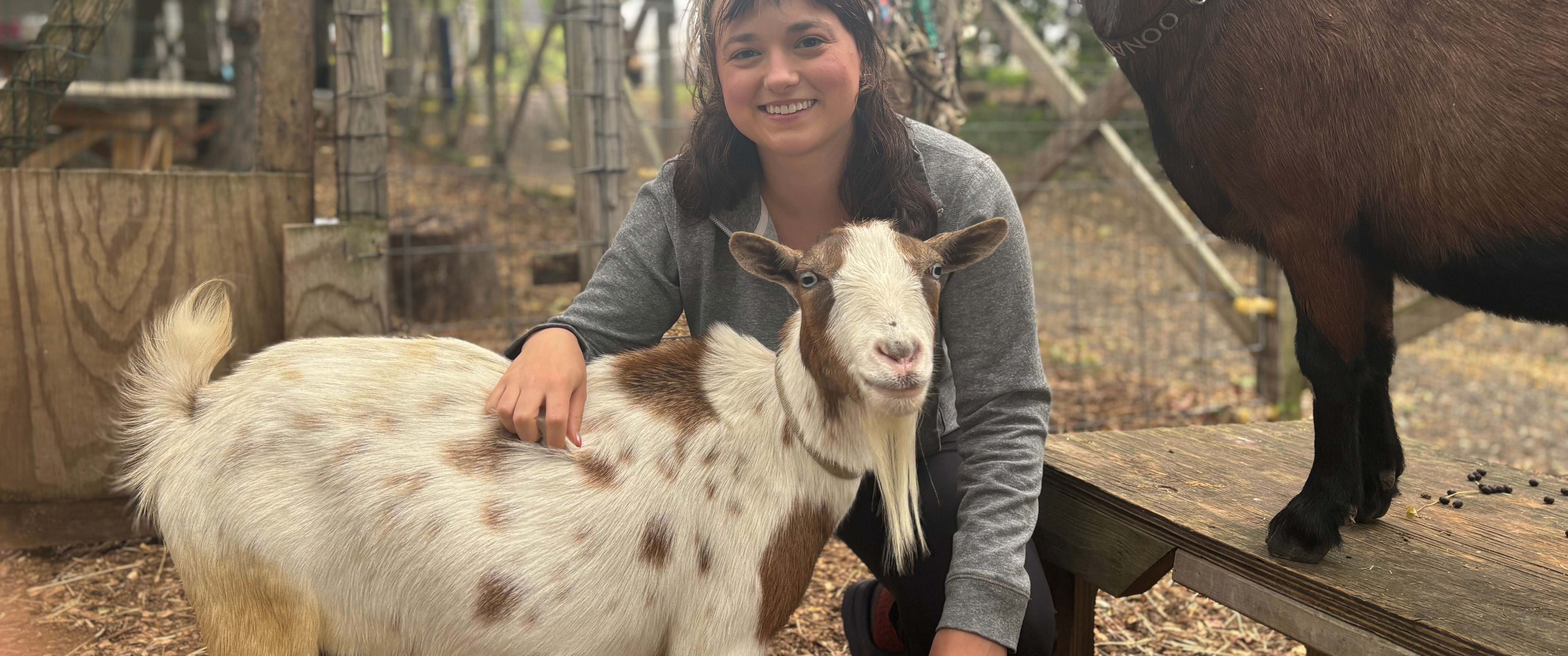 Grace Freund smiling with the two goats on a farm