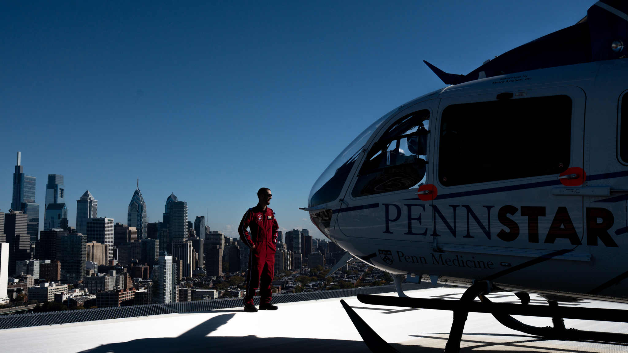 Pilot Eric Houghton inspects a PennSTAR helicopter on the rooftop of the Clifton Center for Health Care Innovation at the Hospital of the University of Pennsylvania with the skyline of Philadelphia in the background