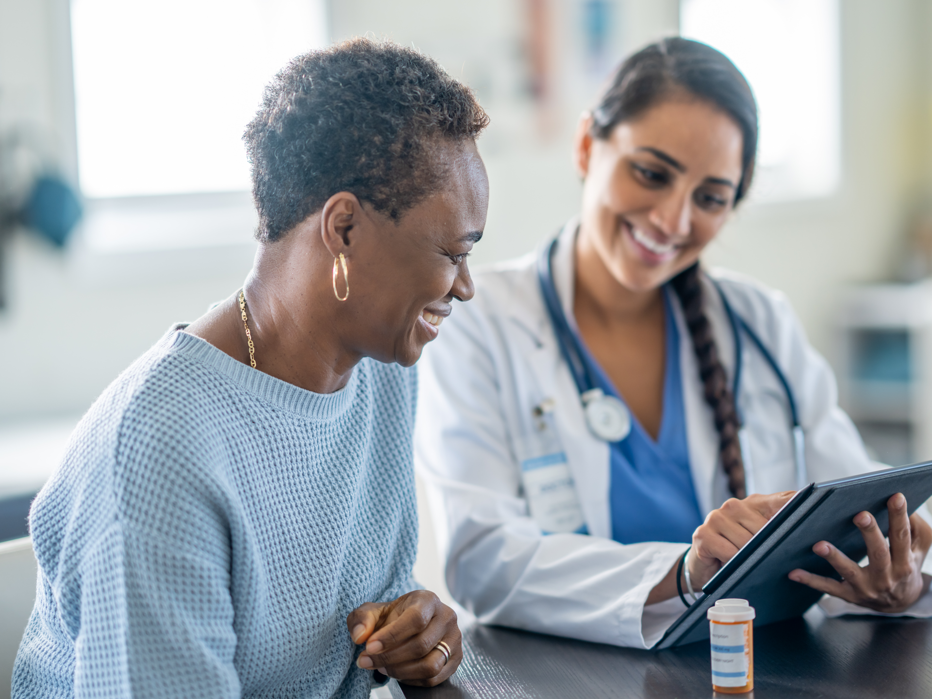 A senior woman meets with her doctor as they review her medications together.