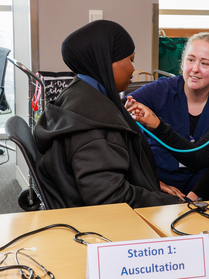 Students practice using a stethoscope as an instructor looks on