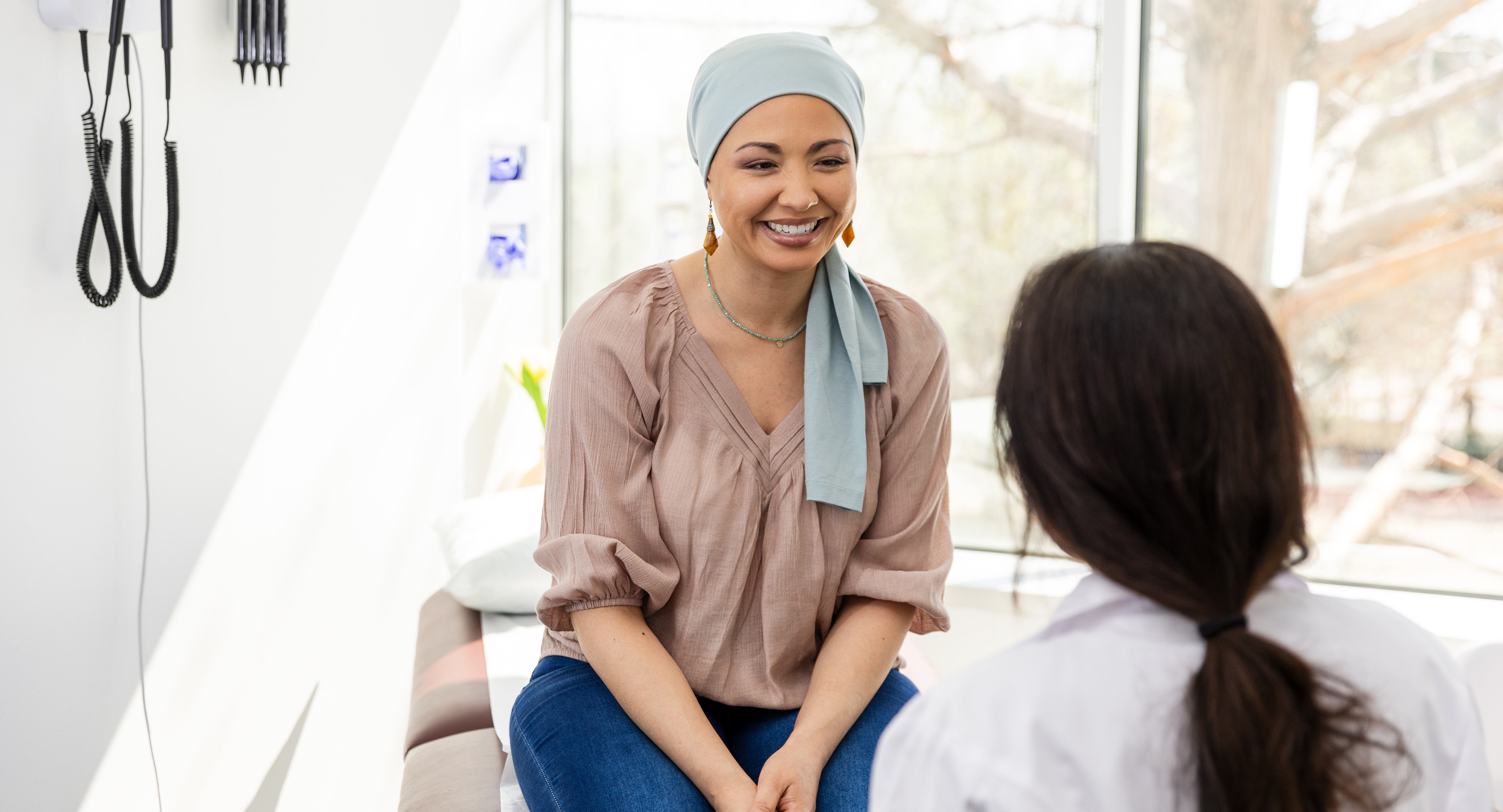  Female oncology patient smiles at unrecognizable female doctor
