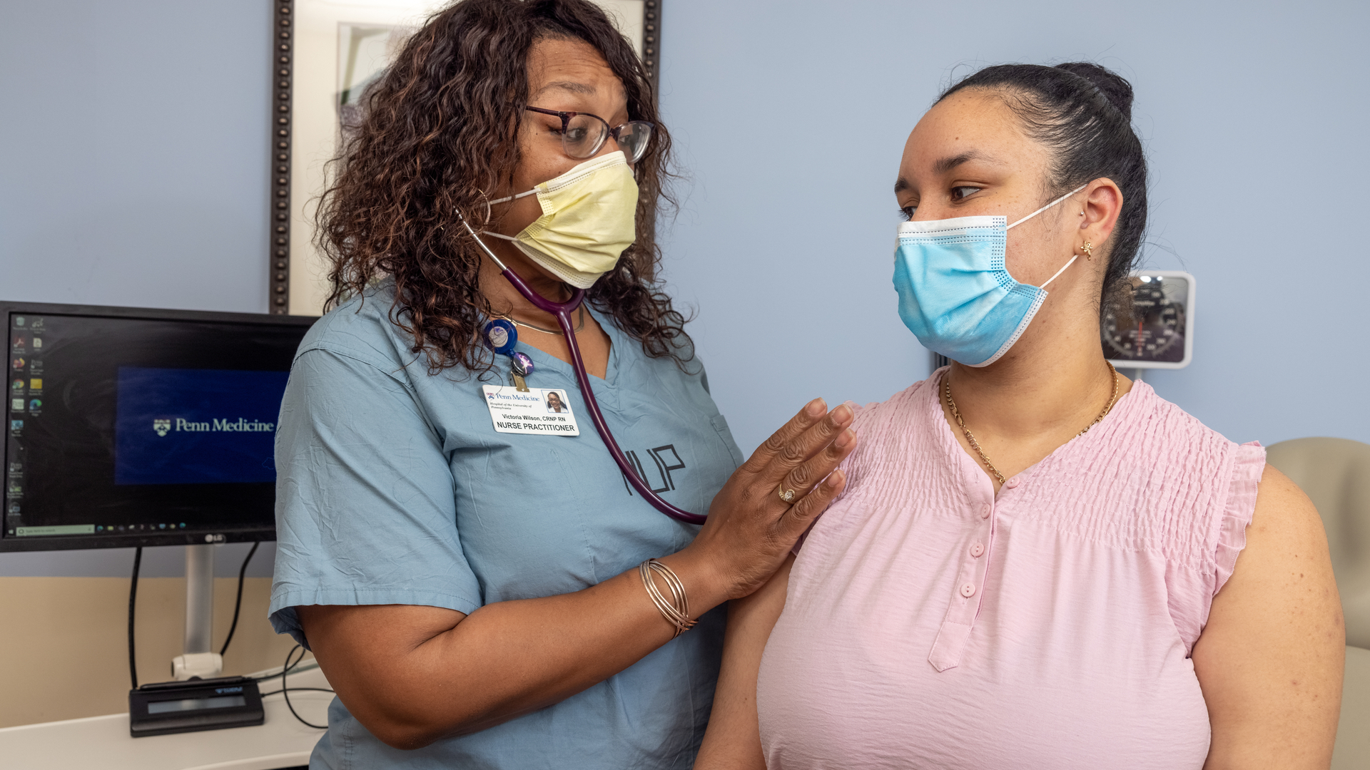 A nurse practitioner wearing HUP scrubs examines a patient