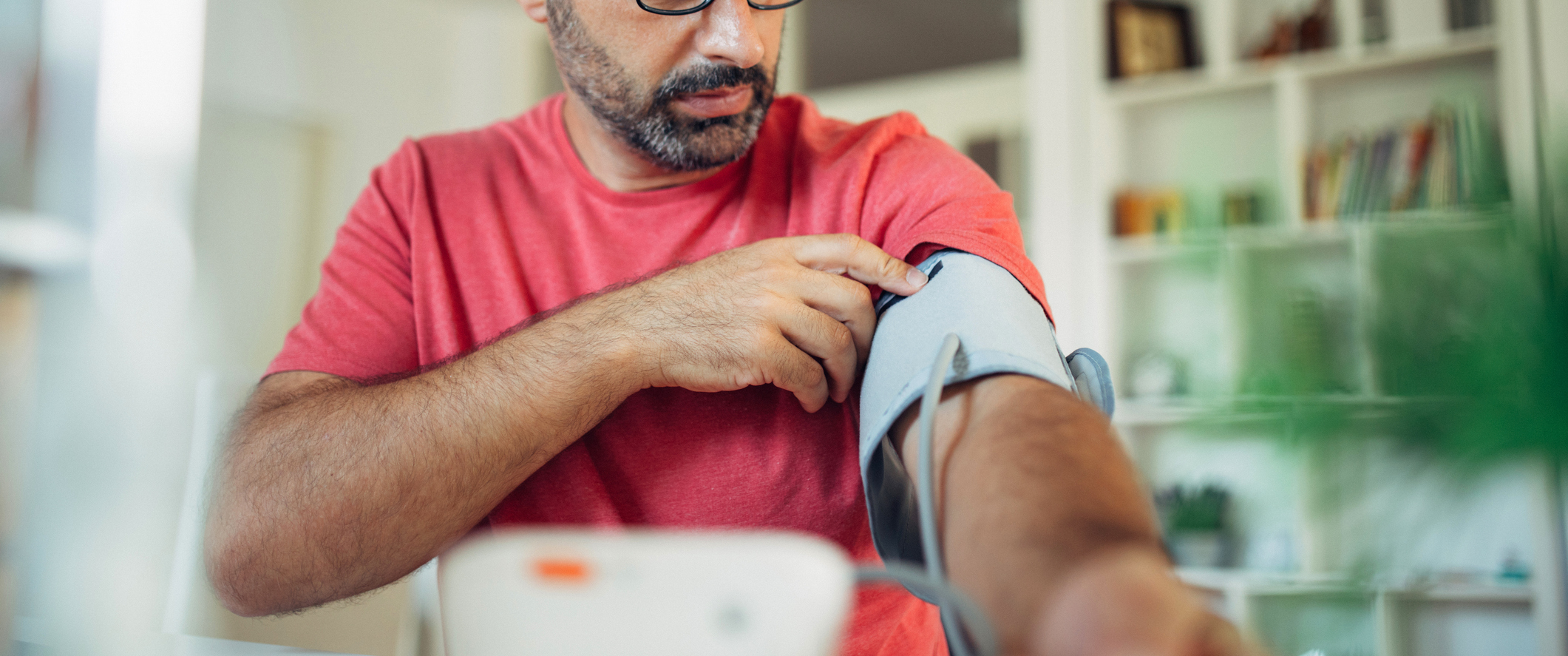 Man putting on a blood pressure cuff at his home.