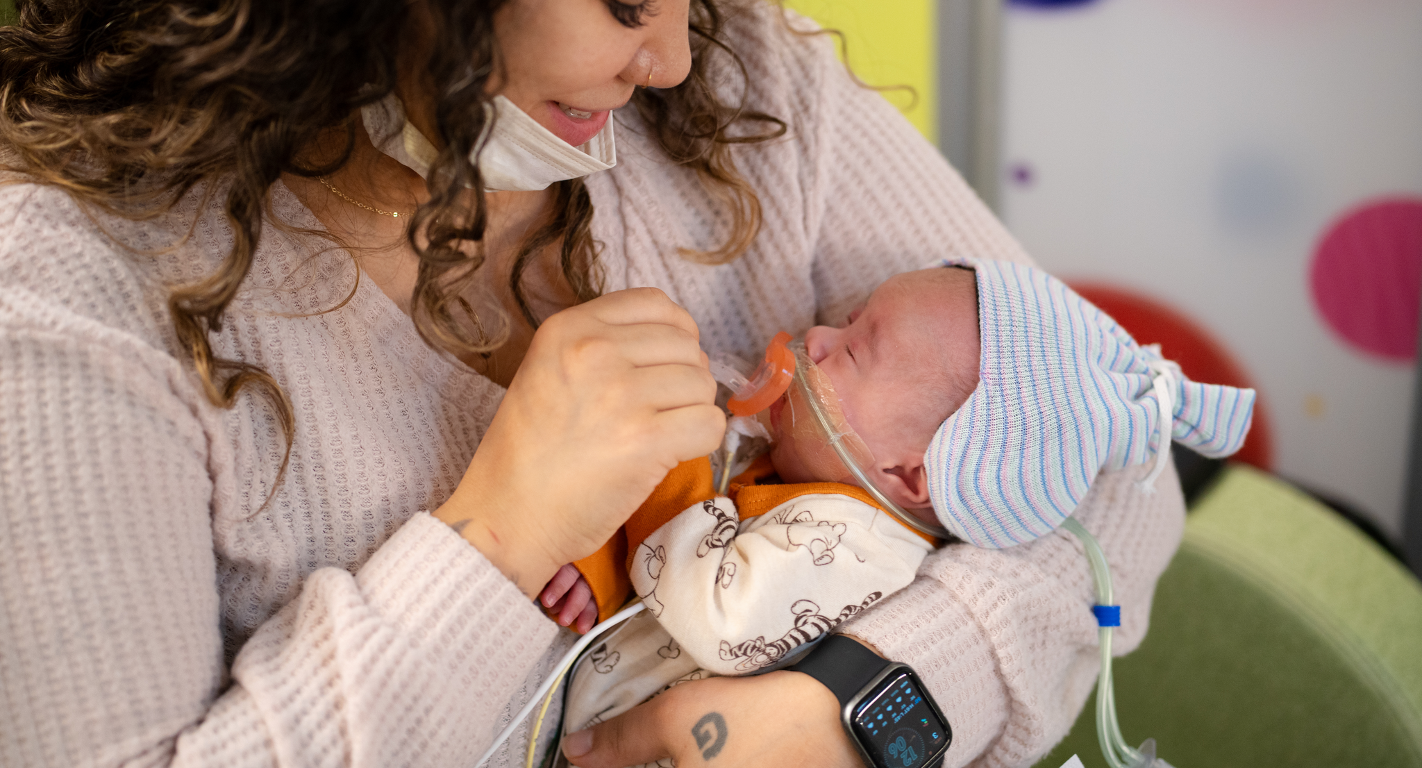 Pamela Collins holding her baby who is wearing a Sonura Beanie in the Intensive Care Nursery