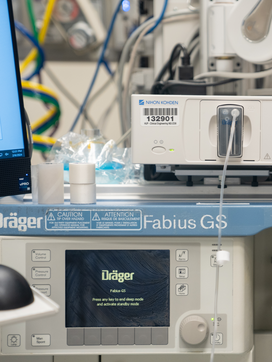 A hand holds up a round magnet with an Earth design and text saying “FGF>MV=WASTE” to encourage anesthesiologists to adjust flow settings.