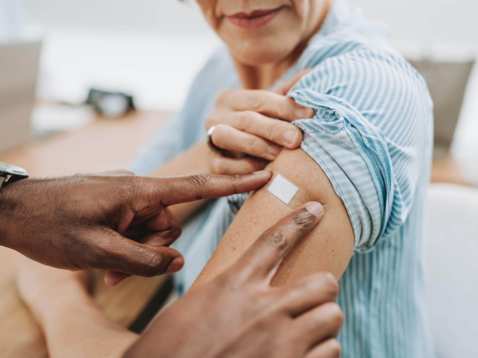 A doctor applies an adhesive bandage to older patient's arm