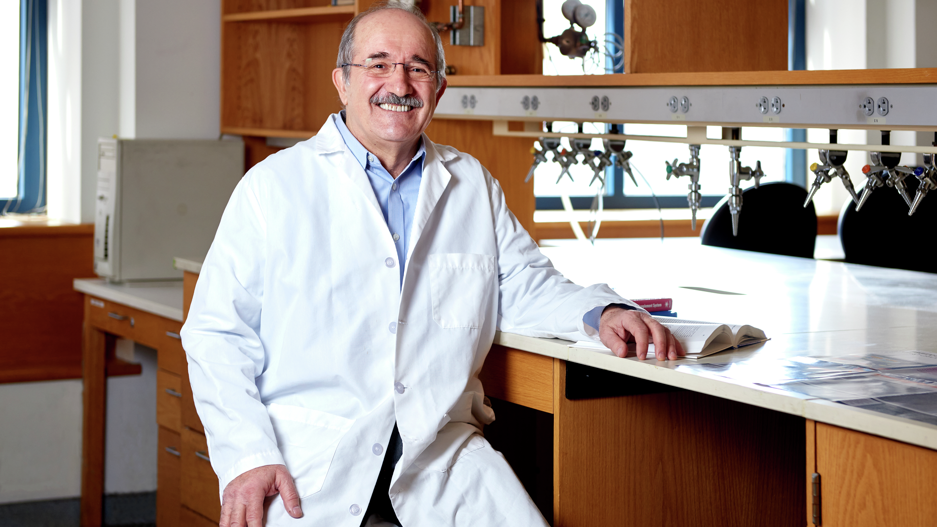 John Lambris sitting at a lab bench, smiling