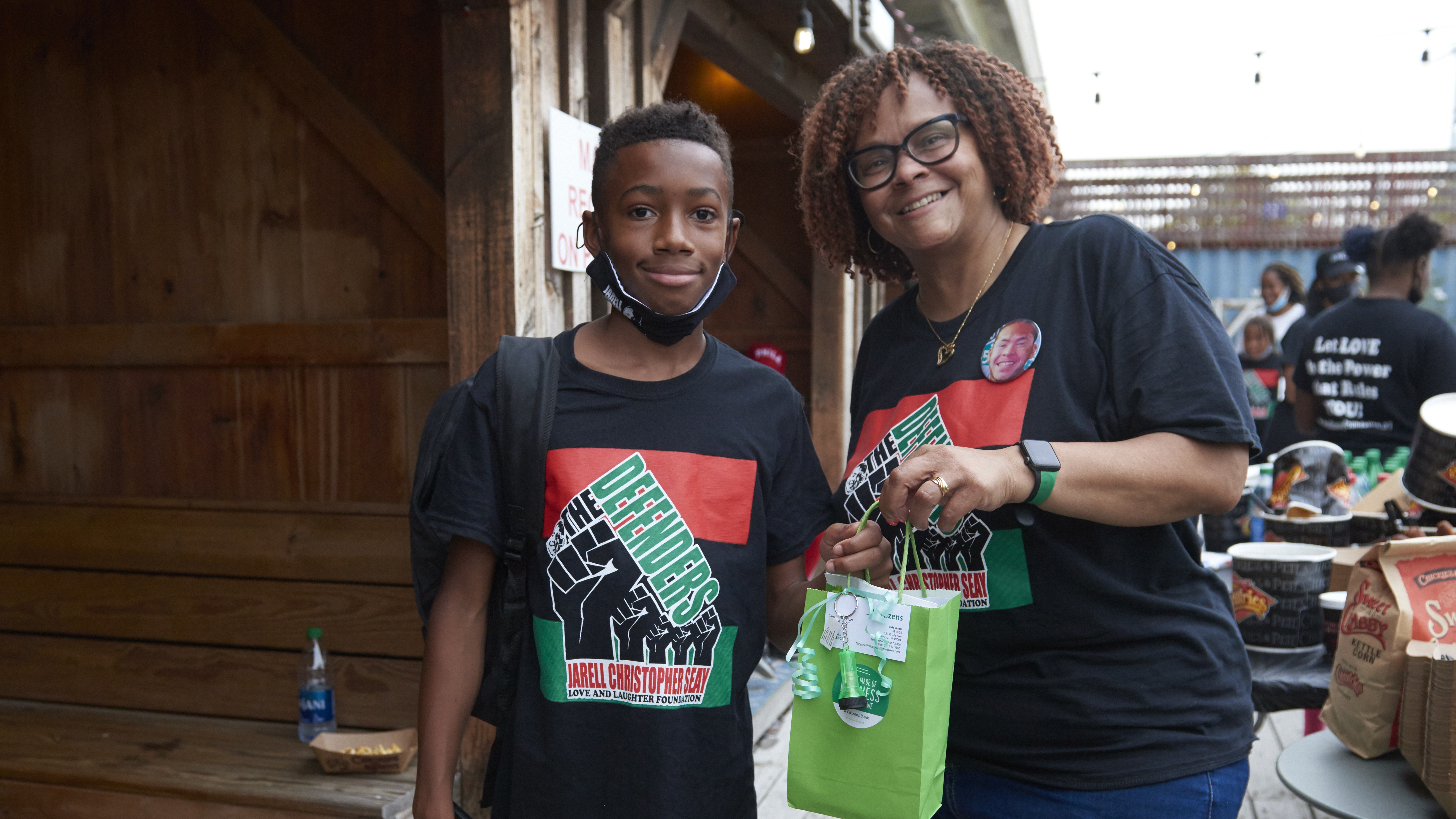 Cherylnne Graham-Seay and a teenage boy both wear Defenders T-shirts, and she holds a gift bag for him