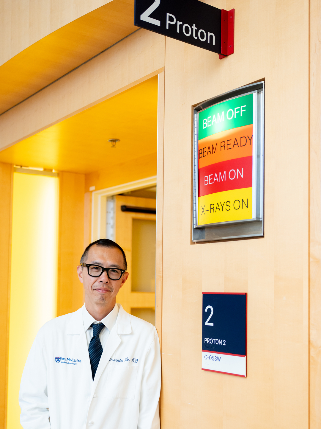 Alexander Lin, MD, stands outside of a proton therapy treatment room