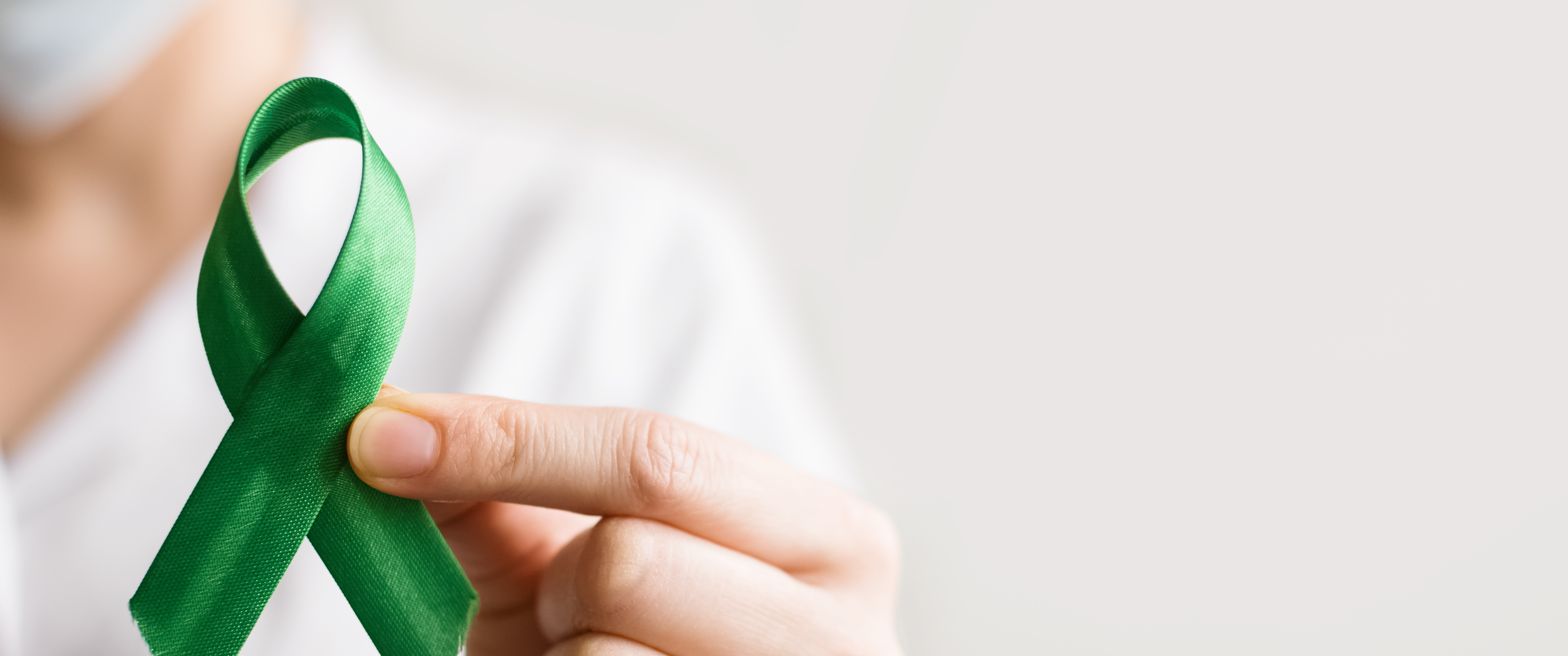 Person holds a green ribbon for kidney transplant awareness