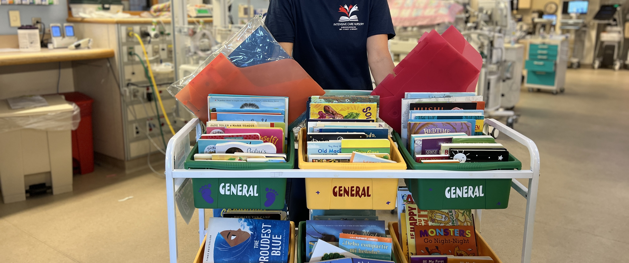 Whitney Zachritz, MSN, RN, CPNP-BC, a nursing professional development specialist at the Hospital of the University of Pennsylvania, stands behind a cart filled with books.