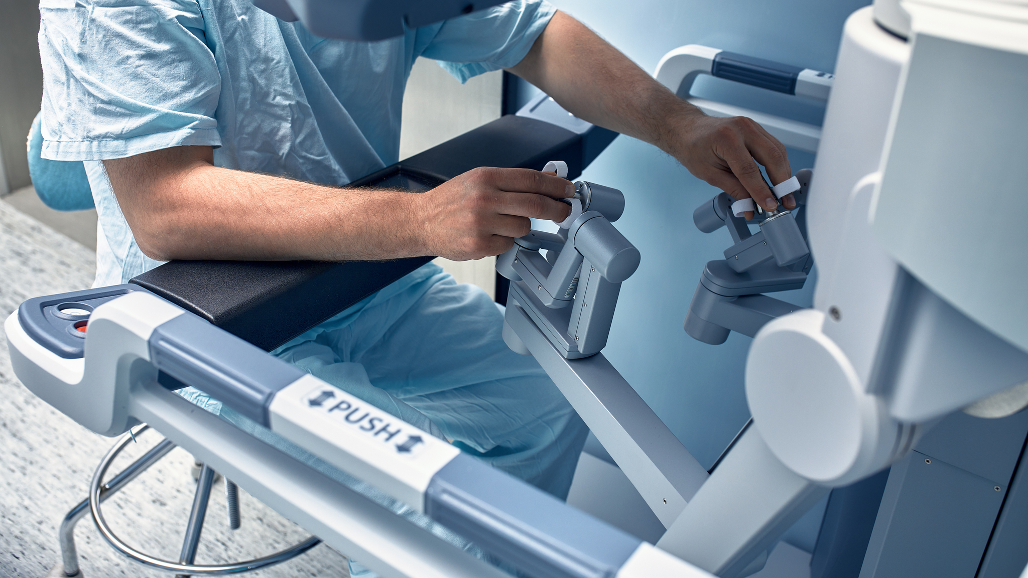 A surgeon controls a robot for surgery