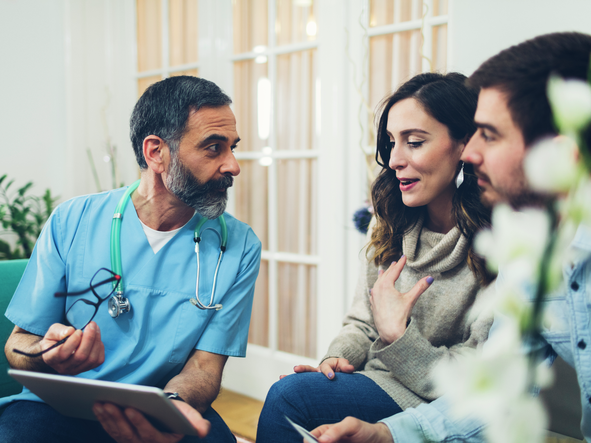 Pregnant woman and her husband at consultation with male nurse in doctors office