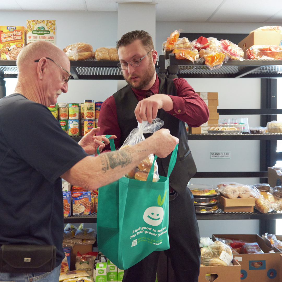 Christopher Moore helps a man place groceries in a bag at a food pantry