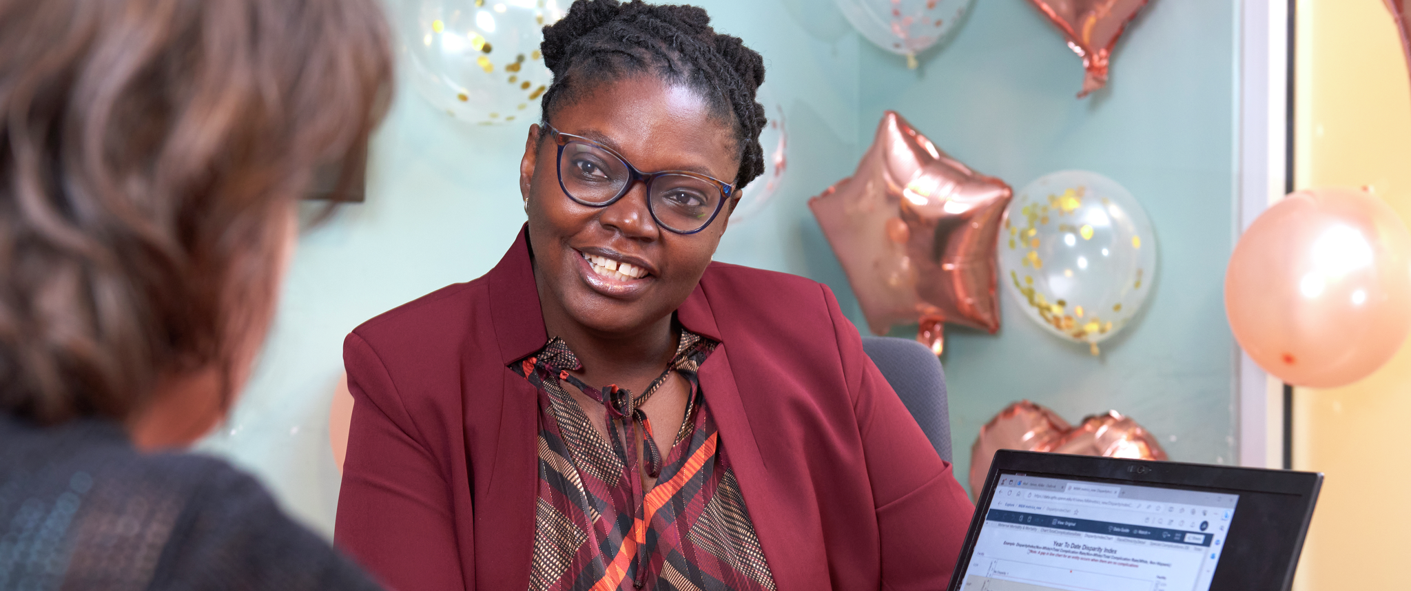 Abike James sits in a conference room with a colleague pointing at data on a laptop screen