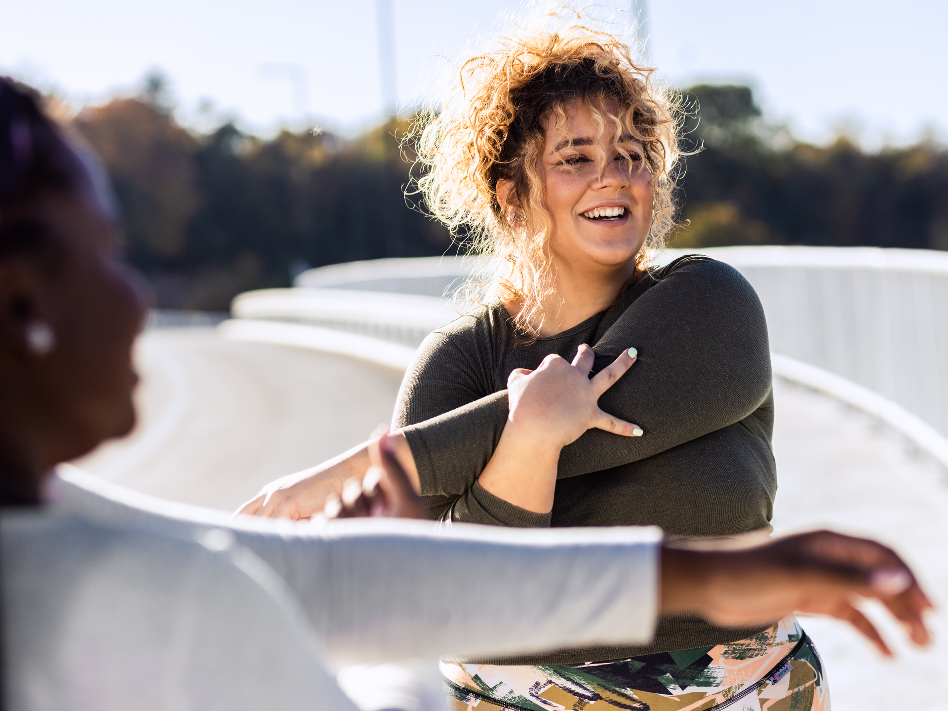  Two young plus size women stretching together before running.