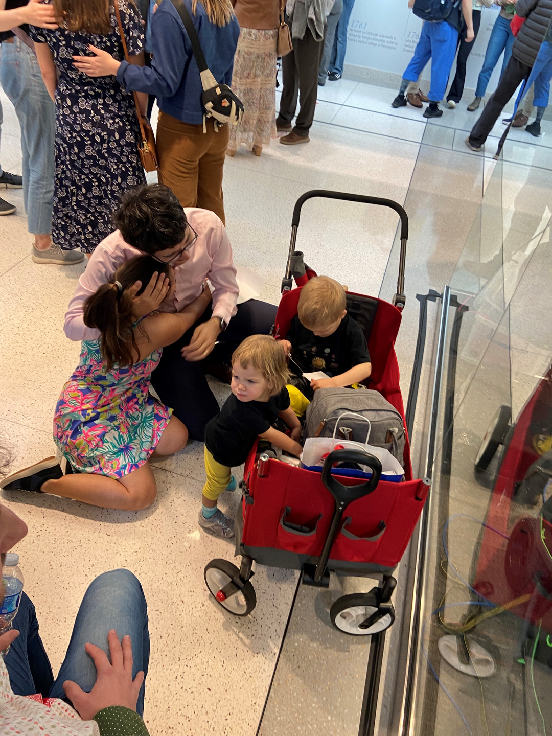 Joseph Aicher and Bernadette Bucher embrace next to their young children sitting in a red wagon.