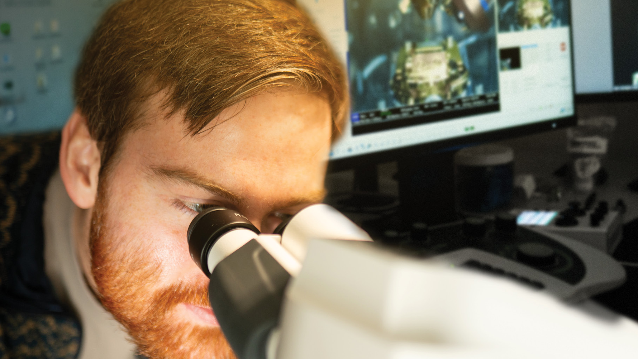 Benjamin Creekmore looks into the eyepiece of a microscope