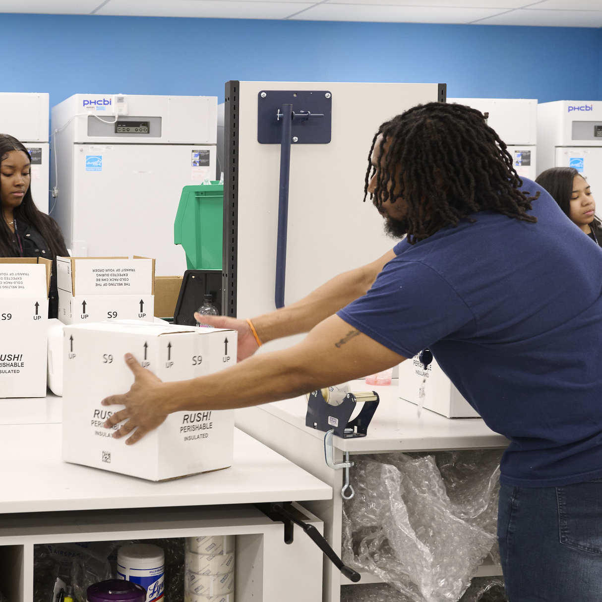 A pharmacist at Penn Medicine’s Specialty Pharmacy stacks white boxes which read ‘Rush! Perishable’ and contain temperature sensitive medications being shipped to patients