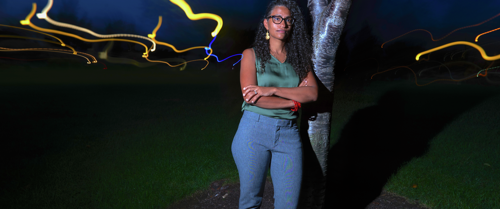 Eugenia South, MD, stands in front of a tree at night, with a motion blur of city lights