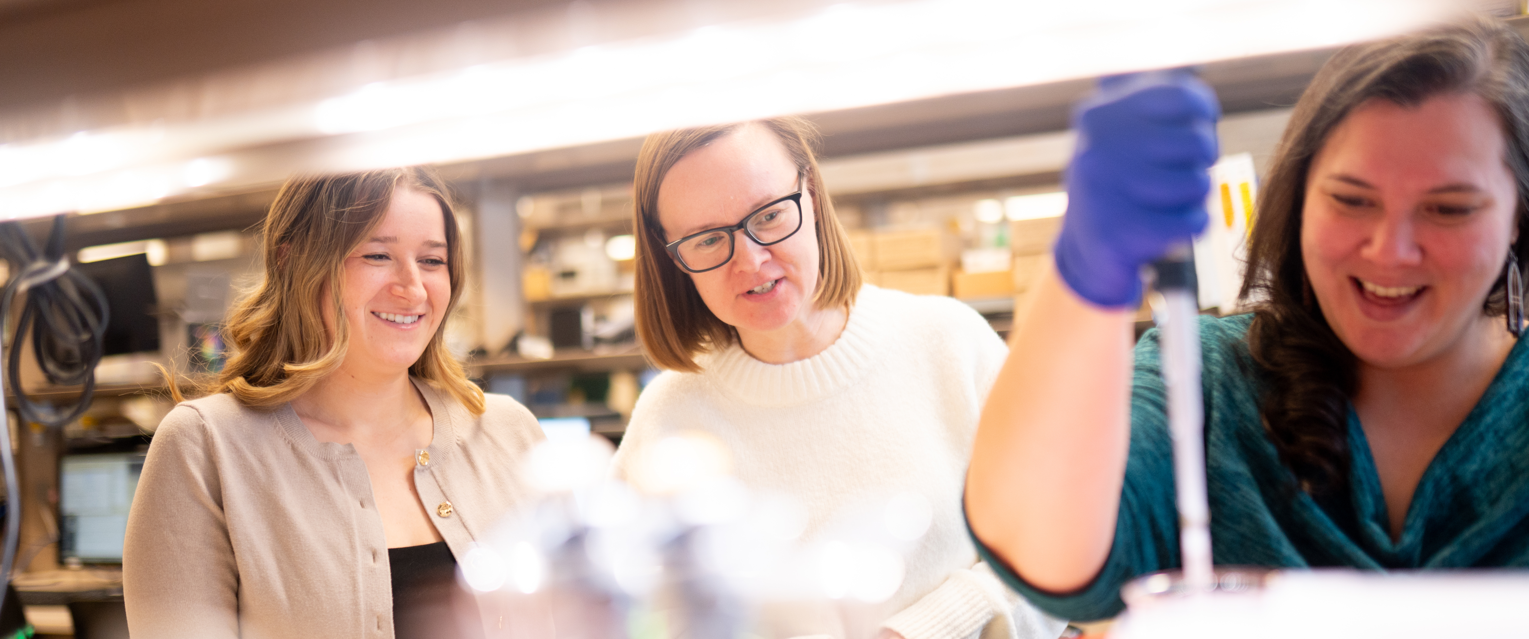 Julia Rocerata, Vera Moiseenkova-Bell, and Ruth Anne Pumroy work together at a lab bench, smiling