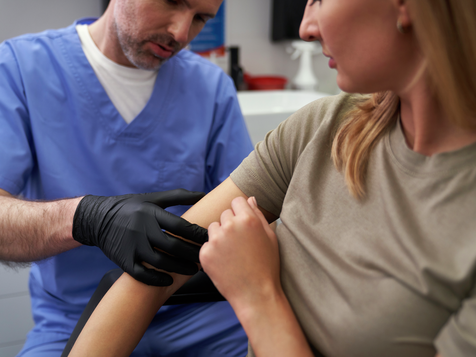 Doctor checking mark on woman's arm.