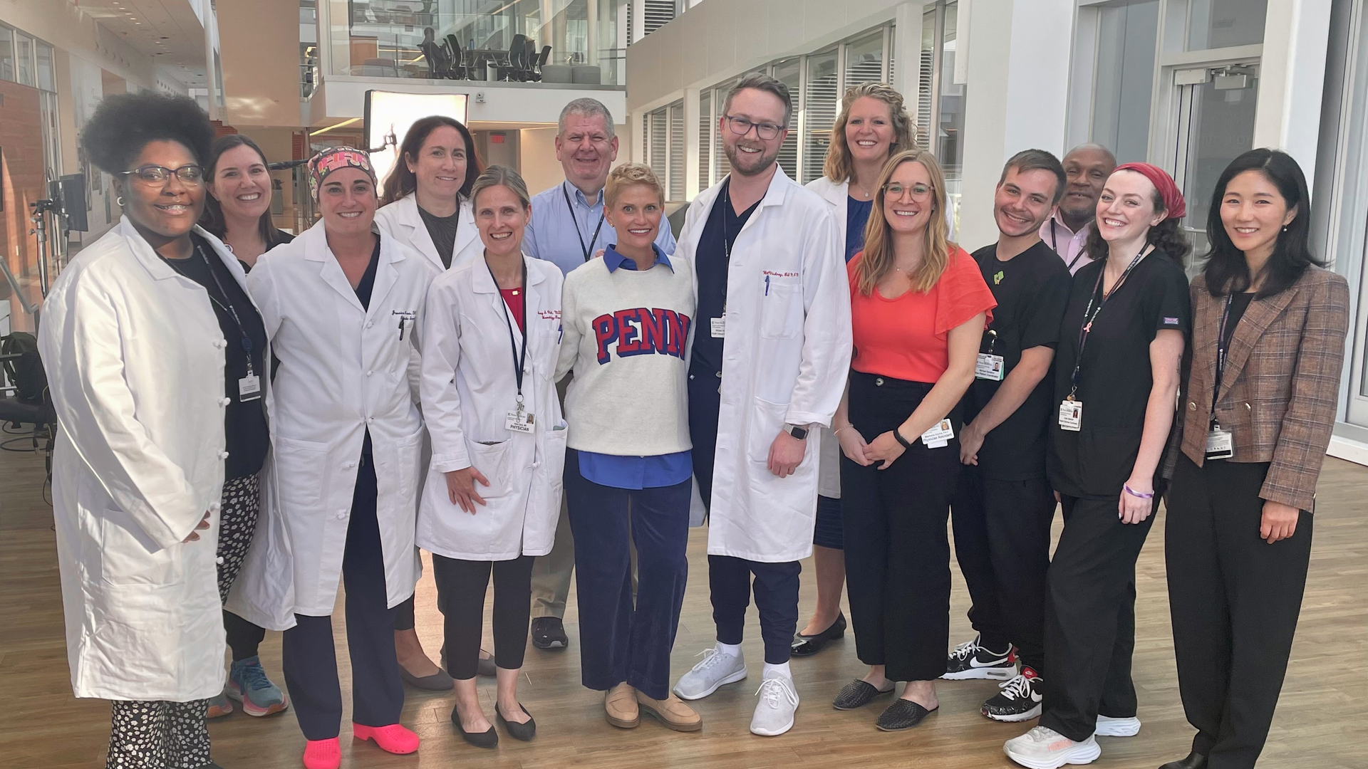 A group of doctors and other staff, with Kate Korson at the center wearing a Penn sweatshirt