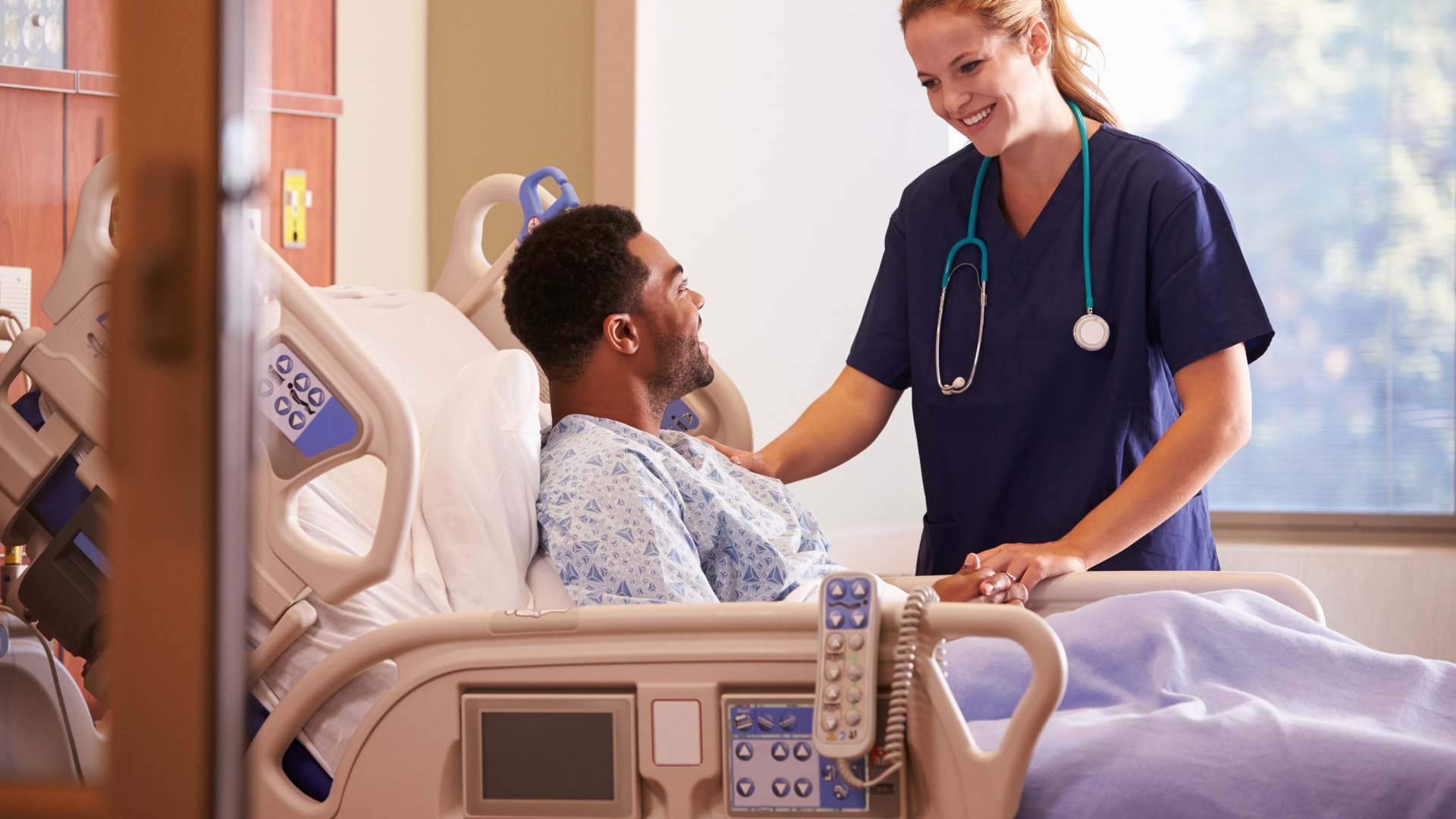 Female doctor talking to male patient in hospital bed