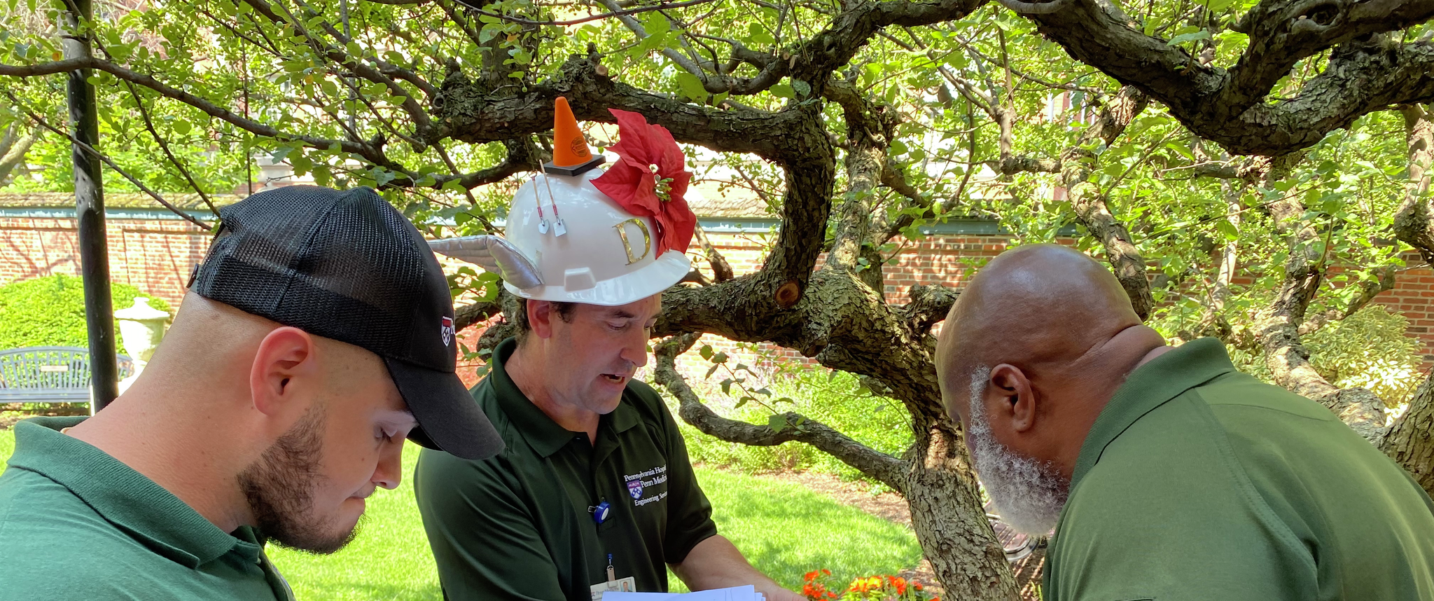 Dan Bangert holds a plant in front of Earl Johnson and Nick Sambucetti, who are writing a list of possible problems and solutions for plants