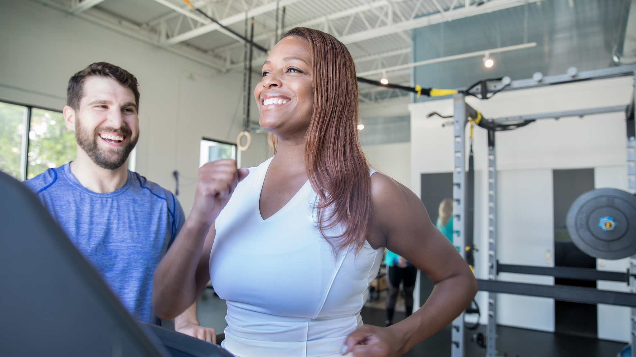 Mature woman running on treadmill while being coached by personal trainer