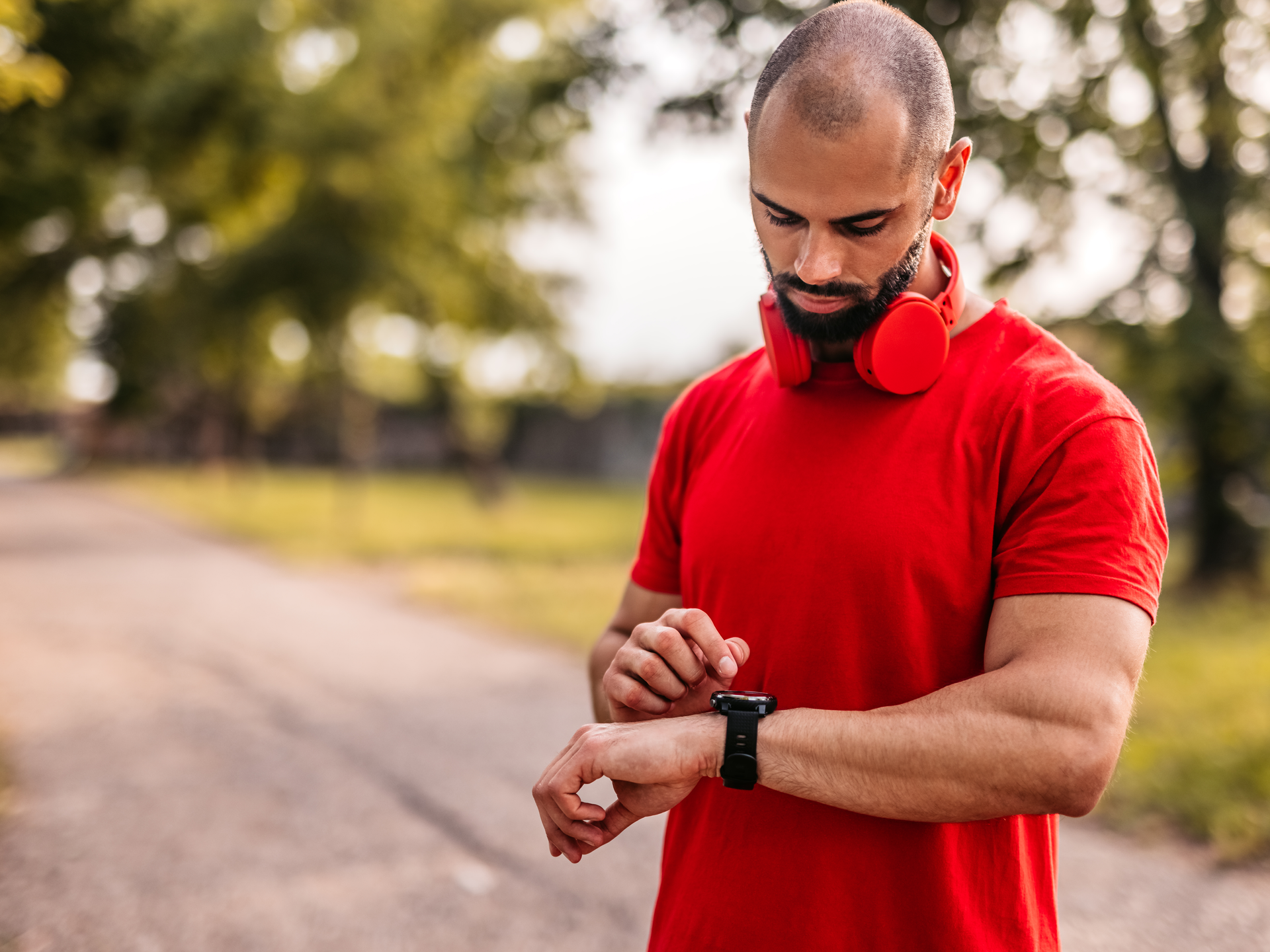 A man checking his watch on a run outdoors.