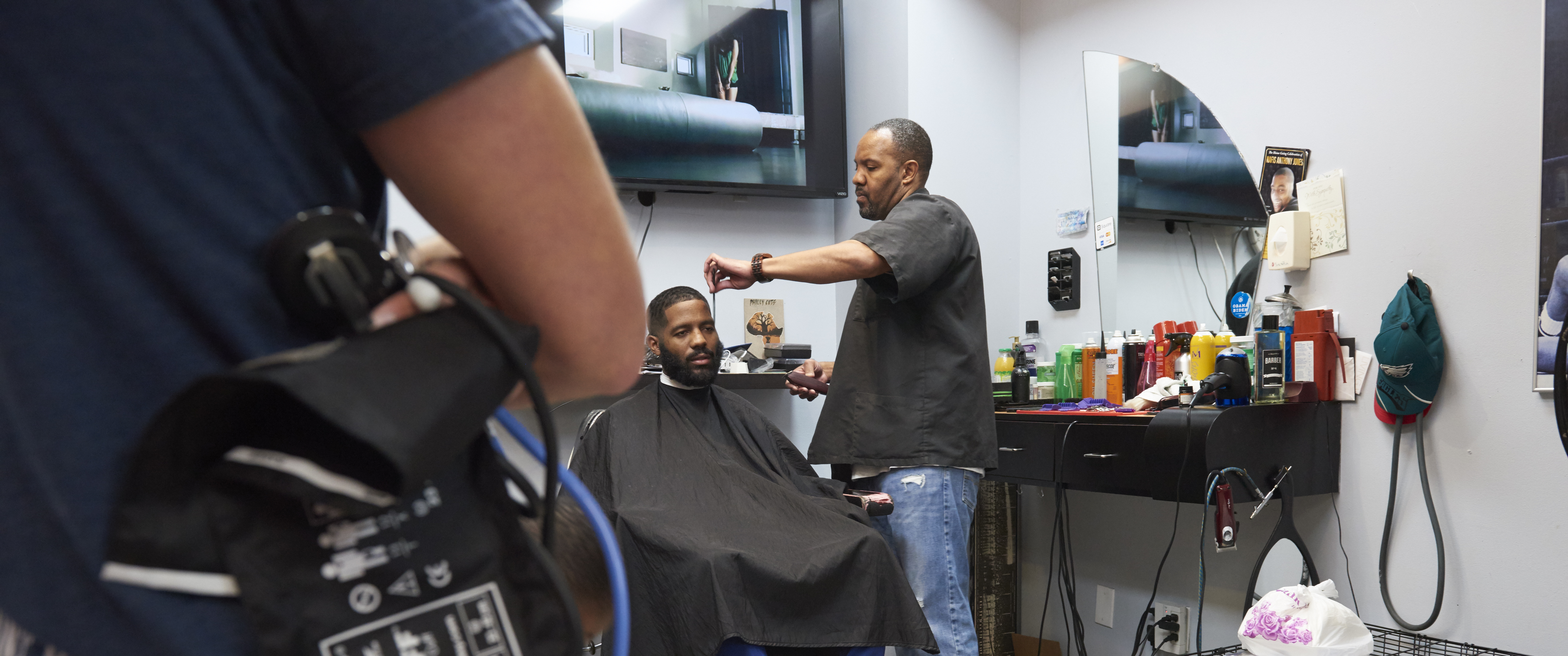 Darryl Thomas cuts a man's hair in a barbershop chair