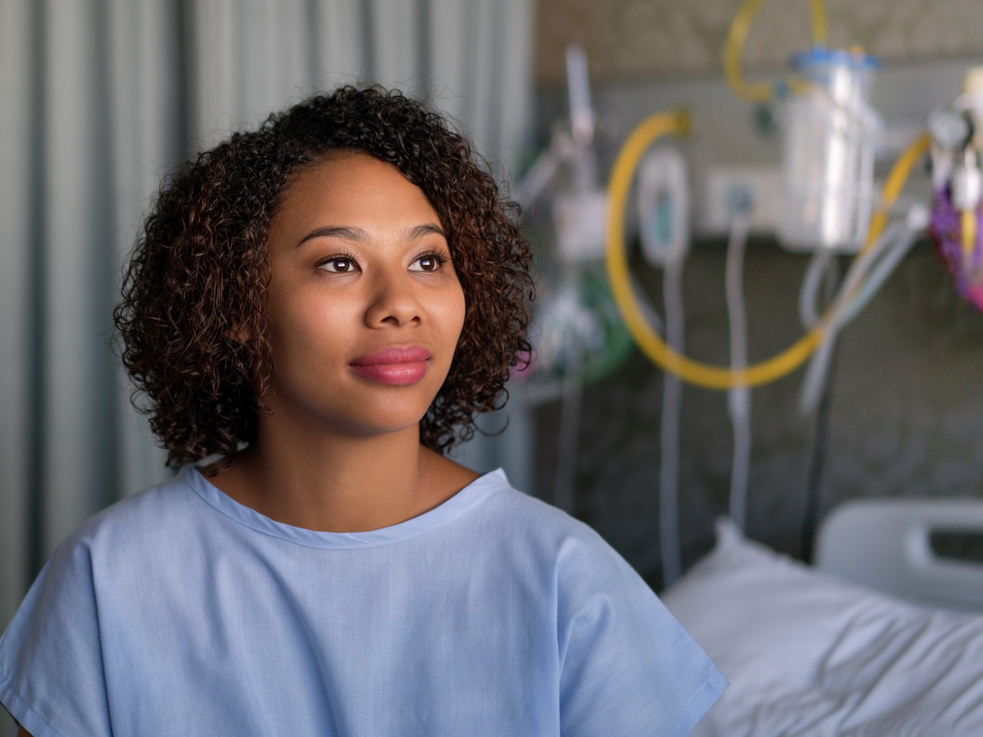 Thoughtful female patient sitting on hospital bed